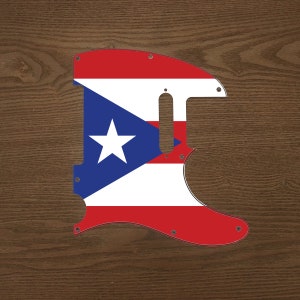 May include: A guitar pickguard with the flag of Puerto Rico. The pickguard is red, white, and blue with a blue triangle and a white star in the center.