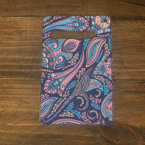 May include: A guitar pickguard with a paisley pattern in shades of pink, blue, and brown. The pickguard has a rectangular shape and is made of a durable material.
