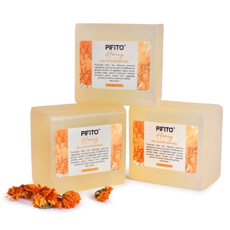 Op de afbeelding: Drie staven transparante, honingkleurige smelt- en gietzeepbasis met de tekst "PIFITO Honey Melt & Pour Soap Base" gedrukt op elke staaf. De staven zijn in een driehoekige vorm op een witte achtergrond gerangschikt.