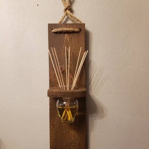 Wood diffuser holder stained in a medium toned brown, handmade. Hang on a wall, holds a glass vase to put diffuser oils and reeds or florals
