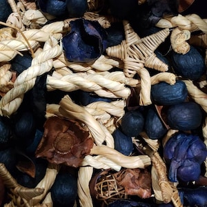 May include: A close-up of a potpourri mix with a variety of natural elements, including dried flowers, woven star shapes, and twisted rope. The mix features a color scheme of dark blue and brown.