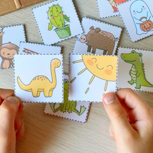 Puede incluir: Un conjunto de tarjetas de memoria coloridas que representan diferentes animales y objetos, incluyendo un dinosaurio, un cocodrilo, un mono, un sol, un cactus, un jabal&iacute; y un fantasma. Las tarjetas est&aacute;n impresas en cartulina blanca con contornos negros y son perfectas para aprender y jugar.
