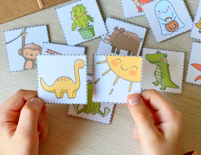 Puede incluir: Un conjunto de tarjetas de memoria coloridas que representan diferentes animales y objetos, incluyendo un dinosaurio, un cocodrilo, un mono, un sol, un cactus, un jabal&iacute; y un fantasma. Las tarjetas est&aacute;n impresas en cartulina blanca con contornos negros y son perfectas para aprender y jugar.