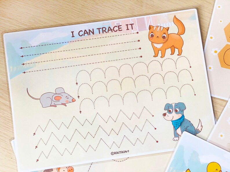 May include: A printable worksheet for kids to practice tracing lines. The worksheet features a cat, a mouse, and a dog, and includes lines to trace in the shape of waves, zigzags, and arches. The text "I can trace it" is at the top of the page.
