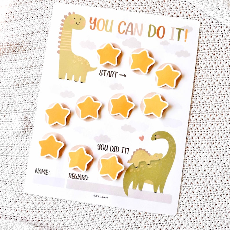 May include: A white reward chart with a dinosaur theme. The chart features the text "YOU CAN DO IT!" and "YOU DID IT!" along with star-shaped stickers. Includes space for a name and reward.