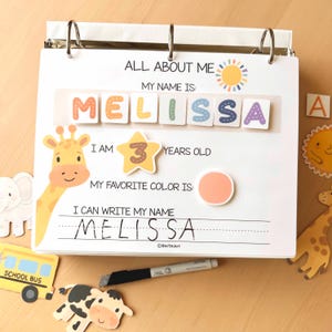 Pode incluir: Uma p&aacute;gina de pasta personalizada "Tudo sobre mim" para uma crian&ccedil;a chamada Melissa. A p&aacute;gina inclui o nome da crian&ccedil;a escrito em letras coloridas, a idade 3 anos e um espa&ccedil;o para escrever o nome. Elementos decorativos: girafa, sol e autocarro escolar.