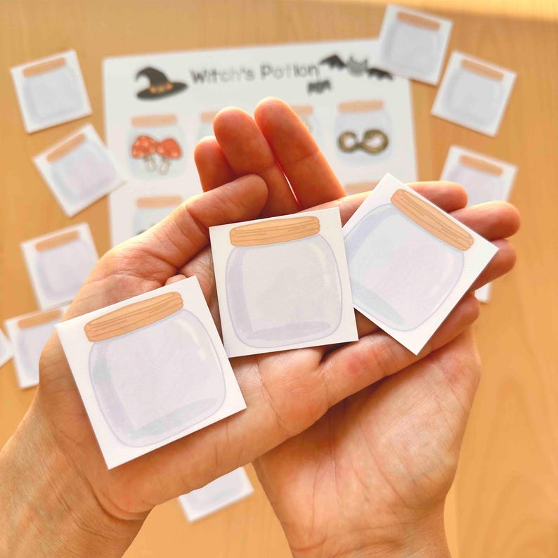 Puede incluir: Tres recortes de papel cuadrados con ilustraciones de frascos de vidrio transparente con tapas de madera de color marr&oacute;n claro. Al fondo, una hoja de papel m&aacute;s grande muestra el texto Witch's Potion junto a varias ilustraciones de frascos.