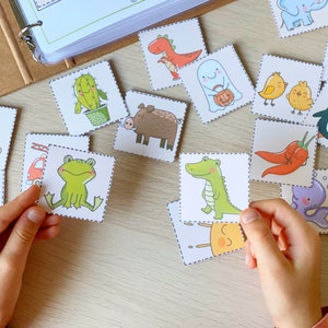 Puede incluir: Un conjunto de tarjetas de memoria coloridas con varios animales, plantas y objetos. Las tarjetas est&aacute;n impresas con ilustraciones bonitas y tienen un fondo blanco con un borde negro punteado.