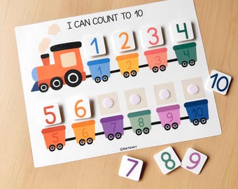 May include: A colorful educational counting board with a train theme. The board features a train graphic and numbered train cars from 1 to 10. Includes separate number tiles for matching. The text "I CAN COUNT TO 10" is displayed at the top.