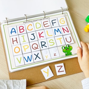 Peut inclure: Un jeu d'association d'alphabet color&eacute; avec des lettres majuscules sur des carr&eacute;s blancs. Les lettres sont de diff&eacute;rentes couleurs et sont dispos&eacute;es en grille. Une grenouille verte se trouve dans le coin inf&eacute;rieur droit de la grille. Les lettres Y et Z sont en bas de l'image.