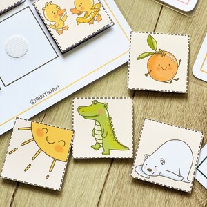 Puede incluir: Un conjunto de tarjetas ilustradas coloridas con una variedad de animales y objetos, incluyendo un sol, un cocodrilo, un oso polar, un pato, una naranja y una bombilla. Las tarjetas est&aacute;n impresas en cartulina blanca y tienen un borde punteado.