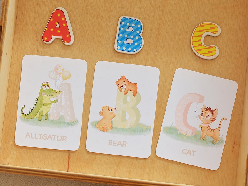 May include: Three colorful alphabet blocks, A, B, and C, with a matching set of flashcards featuring an alligator, bear, and cat. Each card has the letter and the animal's name.