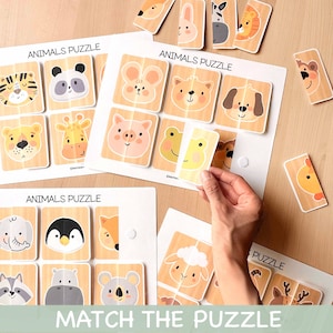 Puede incluir: Rompecabezas de animales de madera con el texto "ANIMALS PUZZLE" y "MATCH THE PUZZLE". Los rompecabezas presentan varias caras de animales, como un tigre, un panda y una jirafa. Una mano sostiene una pieza del rompecabezas, mostrando el proceso de emparejamiento.