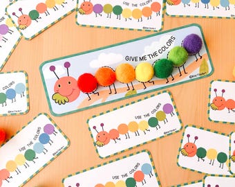 May include: A set of colorful caterpillar-themed learning cards with the words "Give Me The Colors" and "Use The Colors" printed on them. The cards feature a caterpillar with pom-poms for body segments.