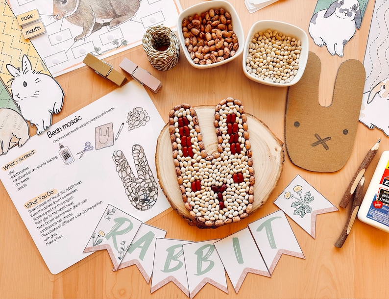 K&ouml;nnte beinhalten: Ein Bastelprojekt zum Erstellen eines Hasenmosaiks mit Bohnen. Das Bild zeigt eine Holzplatte mit einer Hasenform, die mit Bohnen umrandet ist. Au&szlig;erdem sind Schalen mit Bohnen, eine Klebeflasche, eine Schere, Bleistifte und ein bedruckbares Banner mit der Aufschrift "HASEN" zu sehen.