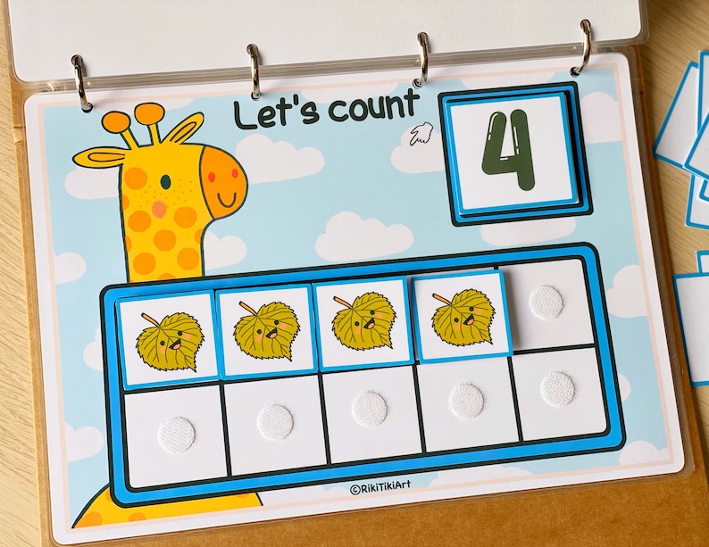 May include: A colorful educational counting activity featuring a cartoon giraffe and leaves. The activity includes a number card with the number "4" and six spaces to count the leaves. The text "Let's count" is written at the top of the page.