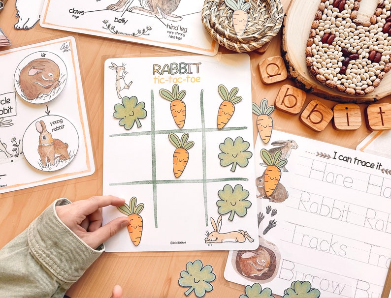 K&ouml;nnte beinhalten: Ein Lernspiel f&uuml;r Kinder mit einem Tic-Tac-Toe-Brett mit Bildern von Karotten und Kleebl&auml;ttern. Das Spiel hei&szlig;t "RABBIT tic-tac-toe".