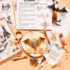 May include: A craft project featuring a wooden slice, pinecones, and paper bat cutouts. The word "BAT" is spelled out with wooden letter blocks. Instructions for making pinecone bats are visible, along with illustrations of different bat species.