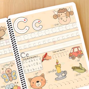 K&ouml;nnte beinhalten: Ein Arbeitsbuch zum Erlernen des Buchstabens C. Die Seite zeigt einen gro&szlig;en Buchstaben C mit gepunkteten Linien zum Nachzeichnen, eine Kuh, ein Auto, eine Kerze, eine Katze und Mais. Die Seite enth&auml;lt auch einen Abschnitt zum Einkreisen aller Buchstaben C in einem Buchstabenraster.