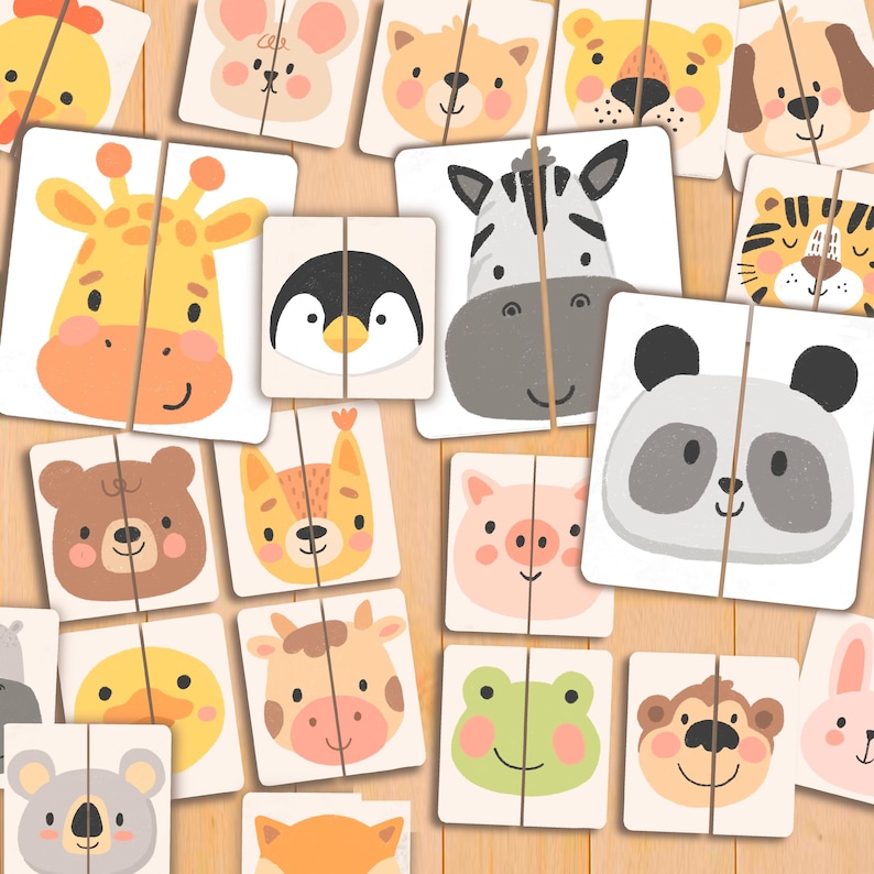 May include: A collection of animal-themed puzzle cards. Each card is divided into two pieces, featuring illustrations of various animals like a giraffe, zebra, panda, and more. The cards are arranged on a light wooden surface.