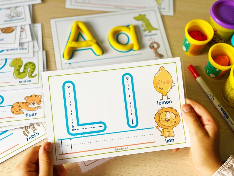 May include: A tracing worksheet for the letter L. The worksheet has a dotted line for tracing the letter L, and pictures of a lemon and a lion. The words "lemon" and "lion" are written below the pictures.