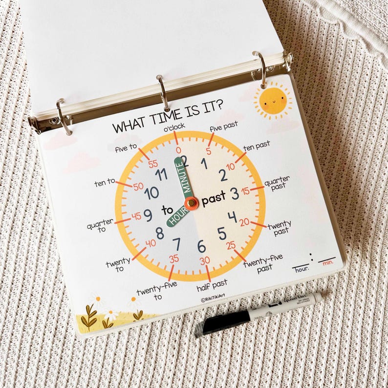 May include: A spiral-bound educational chart with a clock face, designed to teach time-telling. The clock face is yellow with black numbers and labels like "quarter past" and "ten to." The text "WHAT TIME IS IT?" is at the top. A black marker rests below.