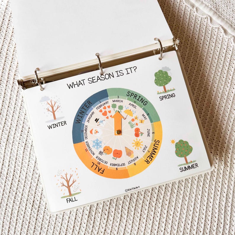 May include: A spiral-bound educational chart titled "WHAT SEASON IS IT?" features a circular design with seasonal illustrations and months. The chart includes images of trees, snowflakes, and fruits, with the seasons labeled: Winter, Spring, Summer, and Fall.