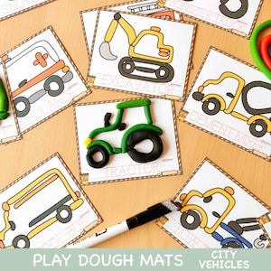 May include: Play dough mats featuring city vehicles. The image shows several cards with outlines of vehicles like an ambulance, excavator, and tractor. A green and black play dough tractor is in the center. A black marker is also visible.
