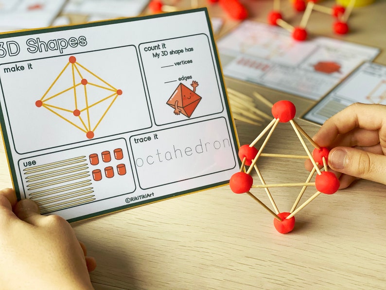 May include: A worksheet with instructions to make and trace an octahedron. The worksheet includes a diagram of a 3D shape with lines and dots, and a section to count the vertices and edges. The worksheet also includes the word "octahedron" written out. A child's hand is holding a model of an octahedron made with sticks and red balls.