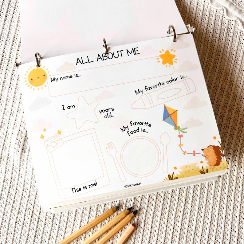 May include: A spiral-bound "All About Me" activity book with a white cover. The cover features illustrations of a sun, crayon, kite, and hedgehog. The book includes prompts for name, age, favorite color, and food. Pencils are at the bottom.