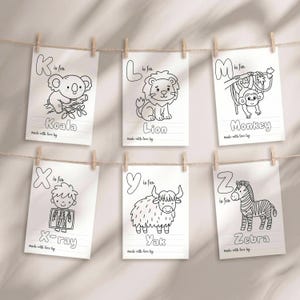 May include: Six white rectangular coloring pages hanging on a string, each featuring a letter of the alphabet, a corresponding animal or object illustration, and the text "is for" and "made with love by". The letters shown are K, L, M, X, Y, and Z.
