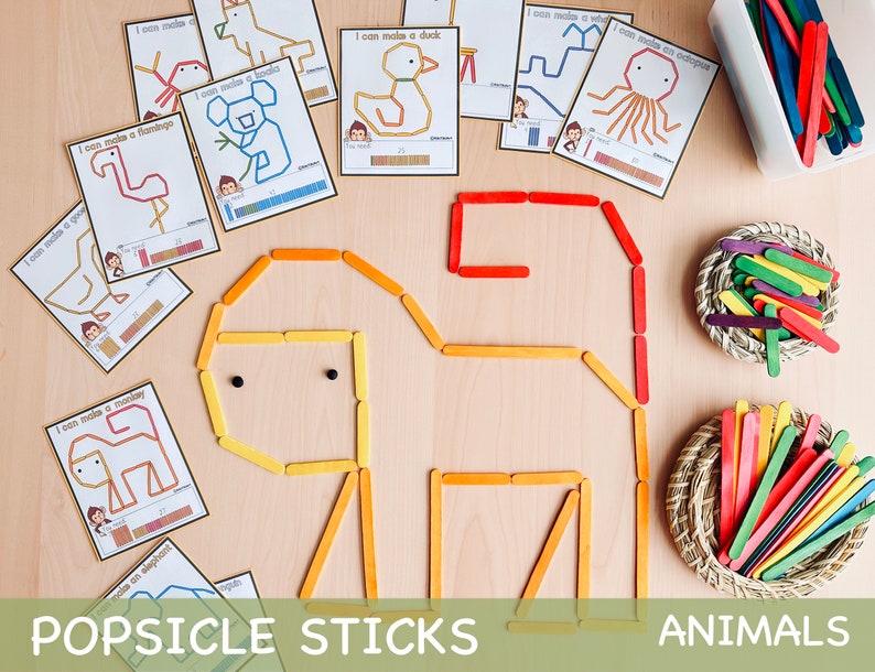 Pu&ograve; includere: Un set di carte stampabili con istruzioni per creare diversi animali usando bastoncini di ghiacciolo. Le carte presentano illustrazioni di un fenicottero, un'anatra, un polpo, un koala, una scimmia e un elefante. Le carte includono anche il numero di bastoncini di ghiacciolo necessari per creare ogni animale. L'immagine mostra anche un animale di bastoncini di ghiacciolo completato, una scimmia e due cesti di bastoncini di ghiacciolo colorati.