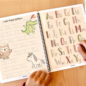 K&ouml;nnte beinhalten: Ein Arbeitsbuch mit einer bunten Alphabet-Spuraktivit&auml;t f&uuml;r Kinder. Das Buch hat einen braunen Einband mit den Worten "I can trace letters" auf der Vorderseite. Die Seiten sind mit Gro&szlig;buchstaben zum Nachzeichnen gef&uuml;llt, sowie Illustrationen einer Eule, eines Einhorns und eines Alligators.