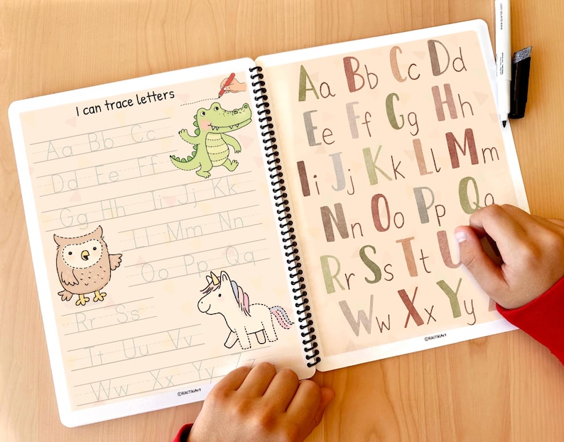 K&ouml;nnte beinhalten: Ein Arbeitsbuch mit einer bunten Alphabet-Spuraktivit&auml;t f&uuml;r Kinder. Das Buch hat einen braunen Einband mit den Worten "I can trace letters" auf der Vorderseite. Die Seiten sind mit Gro&szlig;buchstaben zum Nachzeichnen gef&uuml;llt, sowie Illustrationen einer Eule, eines Einhorns und eines Alligators.