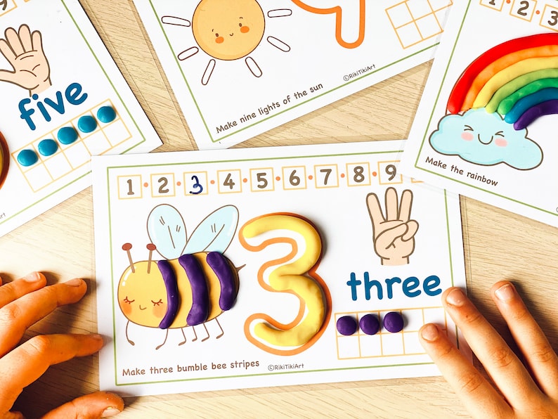May include: A printable learning activity for children to practice counting to three. The activity features a bee with three purple stripes, a large yellow number three, and a hand showing three fingers. The word "three" is written below the hand. There are three purple circles in a grid to count.