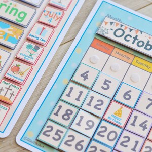 May include: A colorful magnetic calendar with a month of October theme. The calendar features a pumpkin, spiderwebs, and bats. The days of the week are labeled in English. The numbers 1 through 31 are included on the calendar.