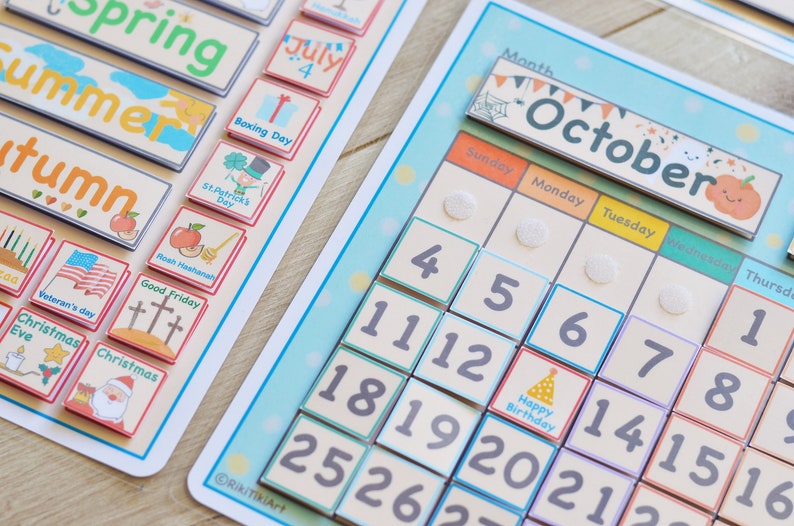 May include: A colorful magnetic calendar with a month of October theme. The calendar features a pumpkin, spiderwebs, and bats. The days of the week are labeled in English. The numbers 1 through 31 are included on the calendar.