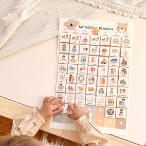 May include: A child's weekly planner with a koala and bear design. The planner features illustrated activity icons for each day of the week. The text "MY WEEKLY PLANNER" is at the top. The child's hands are interacting with the planner.
