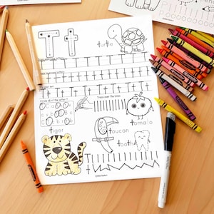 Peut inclure: Une feuille de travail &eacute;ducative pour enfants avec la lettre "T" et des illustrations associ&eacute;es, dont une tortue, un toucan et un tigre. La feuille de travail comprend des exercices de tra&ccedil;age et est entour&eacute;e de crayons de couleur.