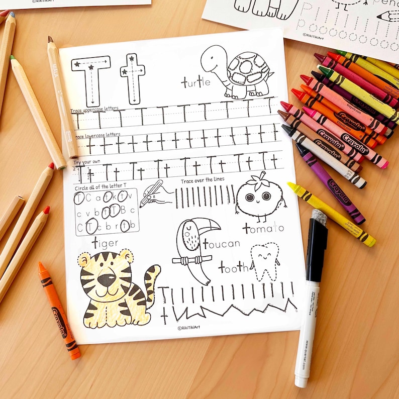 Peut inclure: Une feuille de travail &eacute;ducative pour enfants avec la lettre "T" et des illustrations associ&eacute;es, dont une tortue, un toucan et un tigre. La feuille de travail comprend des exercices de tra&ccedil;age et est entour&eacute;e de crayons de couleur.
