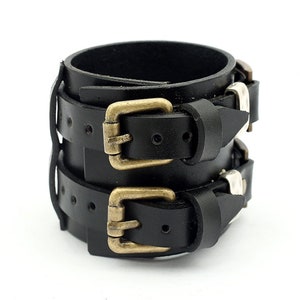 May include: Black leather bracelet with two brass buckles and silver studs.