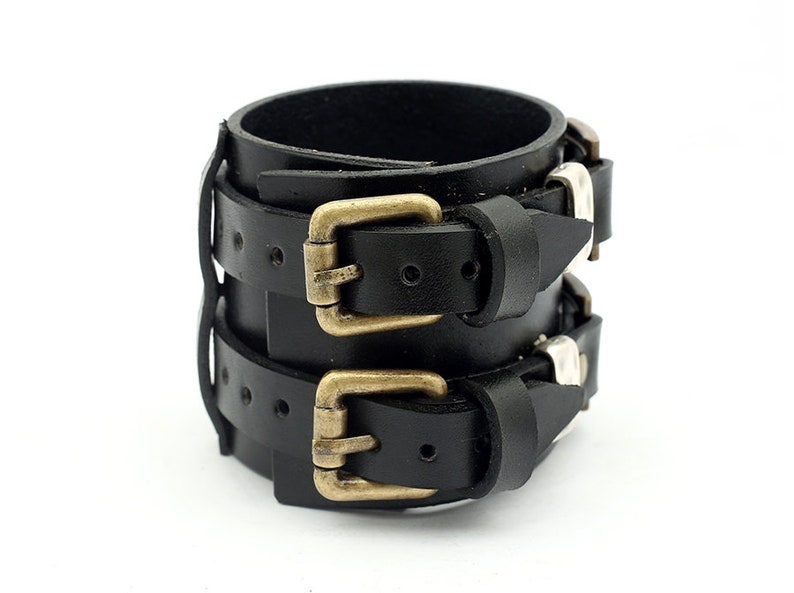 May include: Black leather bracelet with two brass buckles and silver studs.