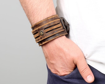 May include: A brown leather cuff bracelet with a star-shaped metal accent and a buckle closure.