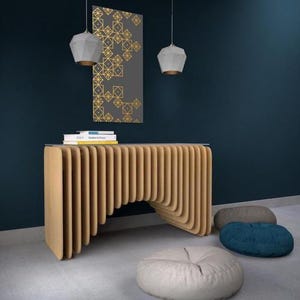 May include: A modern, light brown wooden console table with a curved design, paired with three floor cushions in gray, blue, and white. Two geometric pendant lights hang above. A framed artwork with gold geometric patterns is on the wall.