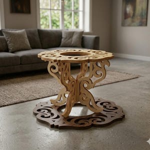 May include: A decorative wooden table with an intricate, openwork design. The table has a round top with a central opening and is supported by ornate, curved legs. It sits on a matching, decorative base. The wood has a natural, light brown color.