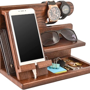 Può includere: Un organizer da scrivania in legno marrone scuro. Dispone di un supporto per telefono, uno slot per portafoglio, un ripiano per occhiali da sole e un vassoio per chiavi e monete. Due orologi sono esposti in alto.