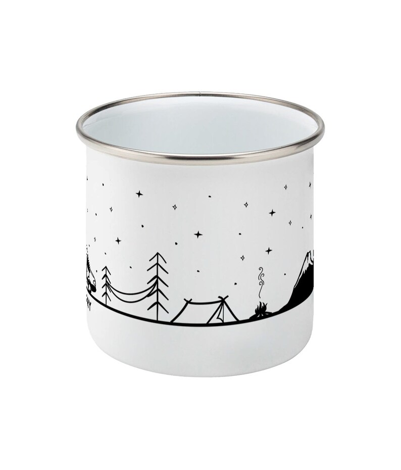 May include: White enamel camping mug with a black and white illustration of a mountain, trees, a tent, and a campfire. The mug has a silver rim.