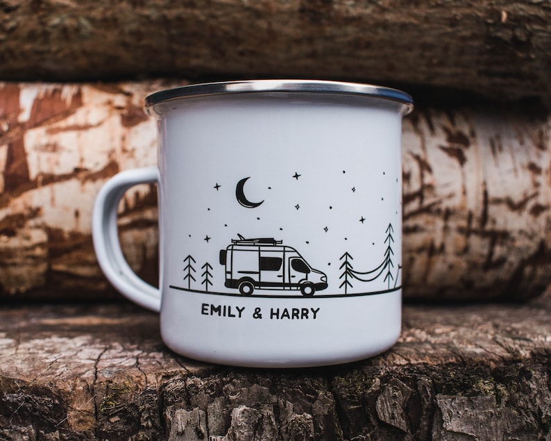 May include: White enamel camping mug with a black and white illustration of a camper van, trees, and a crescent moon. The mug has the text "Emily & Harry" printed on the bottom.