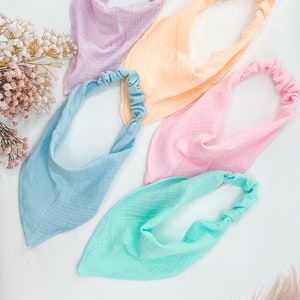 May include: Four fabric headbands in pastel colors: light blue, light pink, light yellow, and light green. Each headband has a gathered elastic band.