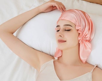 Op de afbeelding: Een vrouw slaapt in bed met een roze satijnen slaapmuts op haar hoofd.